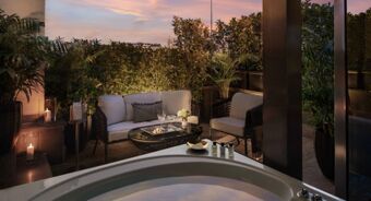 Outdoor seating area with cushioned chairs, a glass table, plants, candles, and a bathtub at Anantara Palazzo Naiadi Rome Hotel Anantara Palazz