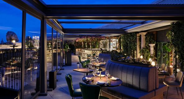 Outdoor evening dining area with tables, chairs, plants, and bar under a covered terrace at Anantara Palazzo Naiadi Rome Anantara Palazz