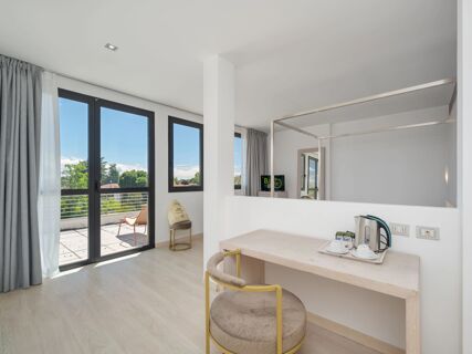 B&B Hotel Padova Methis room with large balcony doors, a chair, a desk with kettle and cups, and light wood flooring