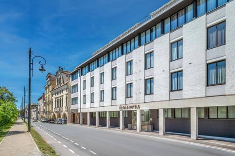 Modern white building with many large windows and street lamps along the road near B&B Hotel Padova Methis under a clear blue sky