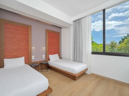 Two single beds with white linens and wooden red-framed headboards next to a large window at B&B Hotel Padova Methis