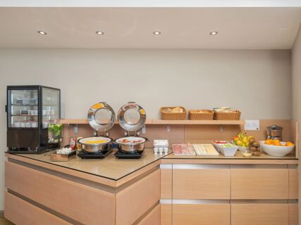 Breakfast buffet with glass refrigerated display, hot food trays, bread baskets, eggs, cold cuts, cheeses, and fruits at B&B Hotel Padova Methis