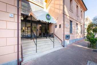 Entrance of B&B Hotel Roma Tuscolana San Giovanni with glass doors, stairs, black railing, and a white canopy with the B&B logo