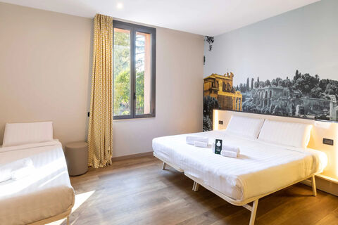 Bright hotel room at B&B Hotel Roma Tuscolana San Giovanni with a large bed, single bed, window with yellow curtains, and scenic wall art