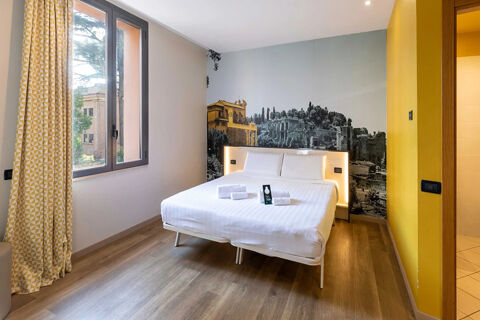 Guest room at B&B Hotel Roma Tuscolana San Giovanni with a double bed, white linens, a cityscape wall mural, and yellow curtains