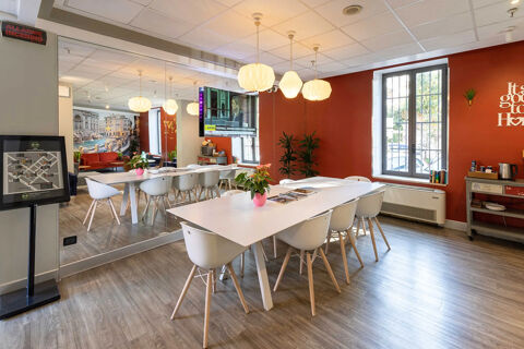 Interior view of a meeting or dining room with white tables, chairs, TV, plants, and decoration at B&B Hotel Roma Tuscolana San Giovanni