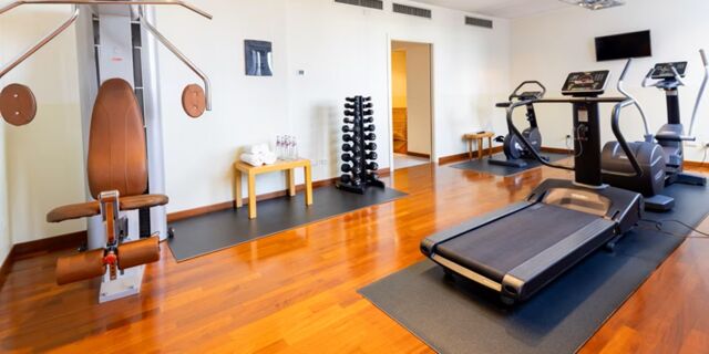 Fitness room with treadmill, stationary bikes, weight machine, dumbbells, and water bottles at Crowne Plaza Venice East