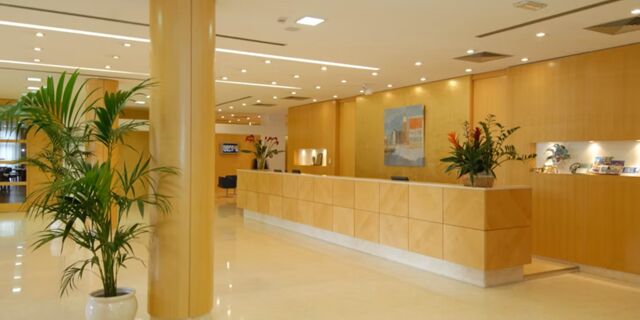 Spacious hotel reception area at Crowne Plaza Venice East with a long wooden desk, potted plants, and wall art displayed