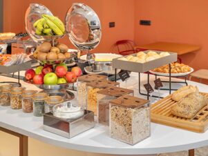 Fruit display with bananas, kiwis, apples, jars of nuts and cereals, bread and pastries at B&B Hotel Milano Cologno Studios