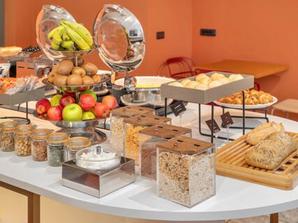 Fruit display with bananas, kiwis, apples, jars of nuts and cereals, bread and pastries at B&B Hotel Milano Cologno Studios