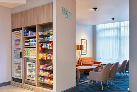 Mini market area with snacks, drinks, and refrigerated items next to a seating space in Leonardo Hotel Southampton