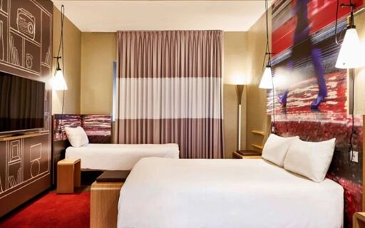 Hotel ibis Milano Centro room with a large bed, single bed, wall art, wooden furniture, red carpet, and modern lighting