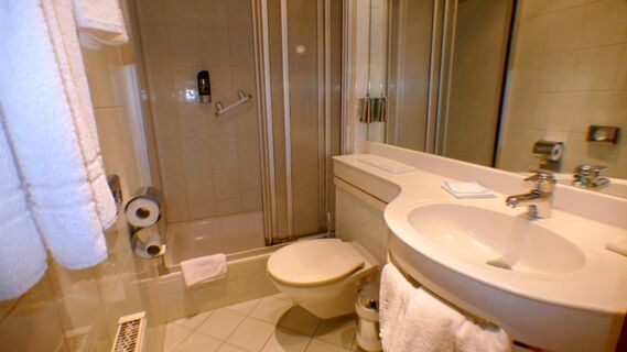 Modernes Badezimmer im Hotel & Metzgerei See mit Dusche, Waschbecken, Toilette und wei&szlig;en Handt&uuml;chern an der Wand.