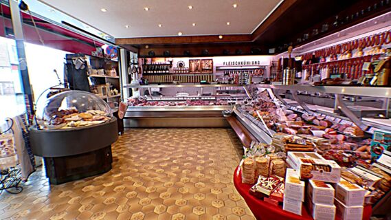 Innenansicht der Metzgerei im Hotel & Metzgerei See mit Fleischtheken, Wurstwaren und regionalen Spezialit&auml;ten auf hellem Boden.