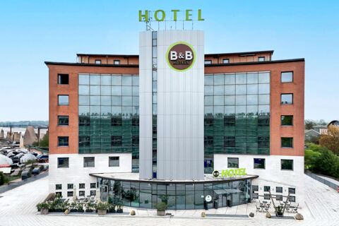 Modern multi-story building with brown brick sides, large windows, and B&B Hotel Padova signage under a clear blue sky