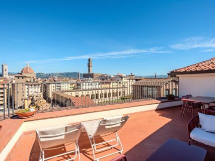 Terrace with two lounge chairs, a table with four chairs, and a view over Florence cityscape at B&B Hotel Firenze Pitti Palace al Ponte Vecchio