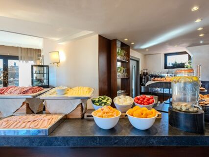 Buffet with sliced meats, cheeses, bowls of cucumbers, tomatoes, boiled eggs, fruit, and infused water at B&B Hotel Firenze Pitti Palace al Ponte Vecchio