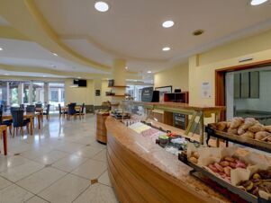Breakfast buffet with cold cuts, croissants, pastries, and seating area in the dining room of B&B Hotel Affi Lago di Garda
