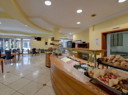 Breakfast buffet with cold cuts, croissants, pastries, and seating area in the dining room of B&B Hotel Affi Lago di Garda