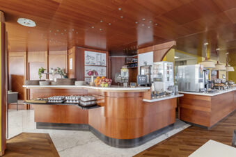 Breakfast buffet area with wooden counters, cups, plates, and fruit baskets at B&B Hotel Modena