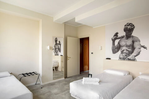Room interior at B&B Hotel Modena with three single beds, white linens, a large statue print, and a wall mirror