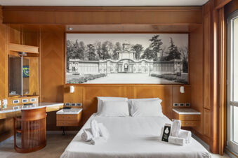 Modern hotel room at B&B Hotel Modena with a double bed, wooden desk and chair, large black and white photo above bed, and window