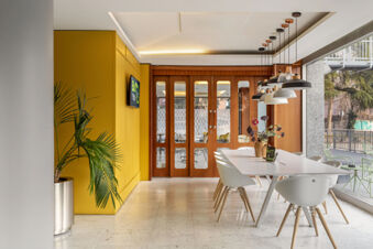 Modern dining area with white table and chairs, hanging lights, wooden doors, and a plant at B&B Hotel Modena