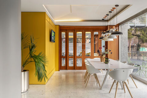Modern dining area with white table and chairs, hanging lights, wooden doors, and a plant at B&B Hotel Modena
