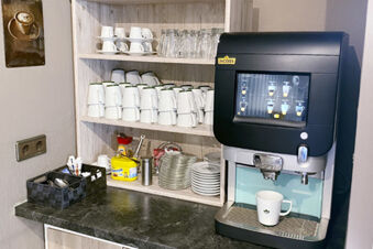 Kaffeeautomat mit Tassen, Gl&auml;sern und Zubeh&ouml;r an einer kleinen Theke im Hotel am Westend f&uuml;r G&auml;stebedienung.