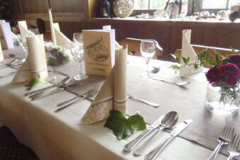 Elegantn&iacute; v&yacute;zdoba stolu se skl&aacute;dan&yacute;mi ubrousky, skleničkami a květinami v restauraci hotelu Landgasthof Niebler.