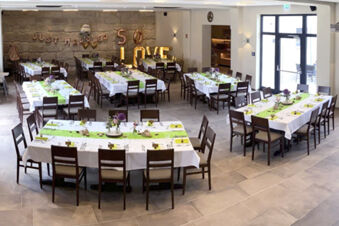 Slavnostně vyzdoben&yacute; hodovn&iacute; s&aacute;l s b&iacute;l&yacute;mi ubrusy a zelen&yacute;mi běhouny v hotelu Landgasthof Niebler, připraven&yacute; na oslavy.