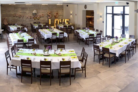 Slavnostně vyzdoben&yacute; hodovn&iacute; s&aacute;l s b&iacute;l&yacute;mi ubrusy a zelen&yacute;mi běhouny v hotelu Landgasthof Niebler, připraven&yacute; na oslavy.