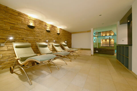 Four modern lounge chairs with cushions and reading lights against a stone wall in a relaxation room at Burg-Hotel Obermoschel