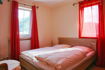 Bedroom at Rheinhotel Zum Anker featuring a double bed with white bedding, red curtains, a window, and beige walls