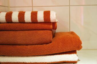 Stack of rust-colored and white towels folded neatly on a tiled surface at Rheinhotel Zum Anker