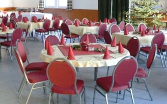 Praznično okra&scaron;ena jedilnica z rdečimi stoli in božičnimi namiznimi okraski v Rheinhotelu Zum Anker.