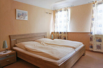 Hotel room at Rheinhotel Zum Anker with double bed, light brown walls, two windows with patterned curtains, and wooden furniture