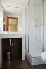 Bathroom in Rheinhotel Zum Anker with a white shower enclosure, tiled walls, a sink with exposed plumbing, and a small trash bin