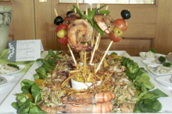 Seafood platter with grilled shrimp on skewers, leafy greens, and other seafood dishes at Landgasthof Bieg