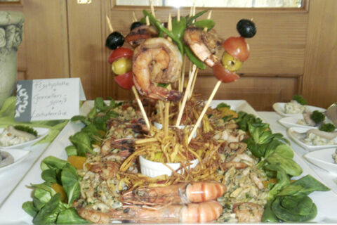 Seafood platter with grilled shrimp on skewers, leafy greens, and other seafood dishes at Landgasthof Bieg