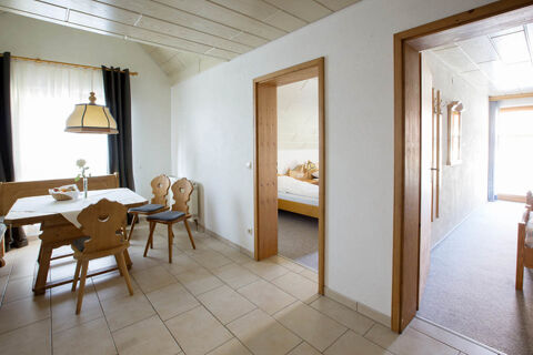 Dining area with wooden table and chairs, two doorways leading to a bedroom and hallway in Landgasthof Bieg