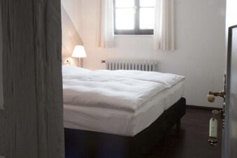 Minimalistic hotel room at Landgasthof Restaurant Adler with a neatly made double bed, bedside lamp, and window with curtains