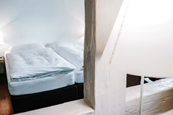 View of a white bed with two pillows and folded duvets next to a bedside lamp at Landgasthof Restaurant Adler