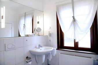 Alt N&uuml;rnberg Hotel 明亮而現代化的浴室，配有洗臉盆、大鏡子和帶窗簾的窗戶。