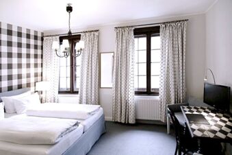 Alt N&uuml;rnberg Hotel 明亮的飯店房間，內有兩張床位、裝有白色窗簾的窗戶，以及一張附有椅子的桌子。