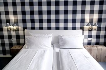 Alt N&uuml;rnberg Hotel 裝潢明亮的客房，配有兩張單人床、白色床單以及灰、黑、白三色的棋盤紋牆壁。