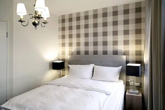 Alt N&uuml;rnberg Hotel 裝潢現代化的飯店房間，牆上有棋盤紋圖案、雙人床和照明設備。