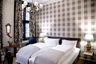 Alt N&uuml;rnberg Hotel 舒適的雙人房，配備現代燈具、圖案窗簾和棋盤格紋壁紙。