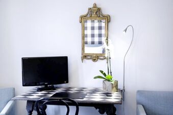 Alt N&uuml;rnberg Hotel 現代化的工作區，配備黑色電視、漆板式辦公桌和金框鏡子。