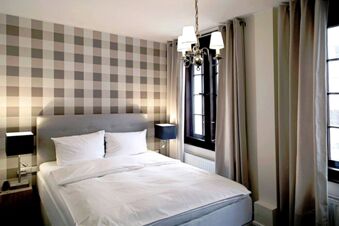 Alt N&uuml;rnberg Hotel 的臥室裝潢現代化，牆紙圖案為棋盤格紋，床大且有窗簾。